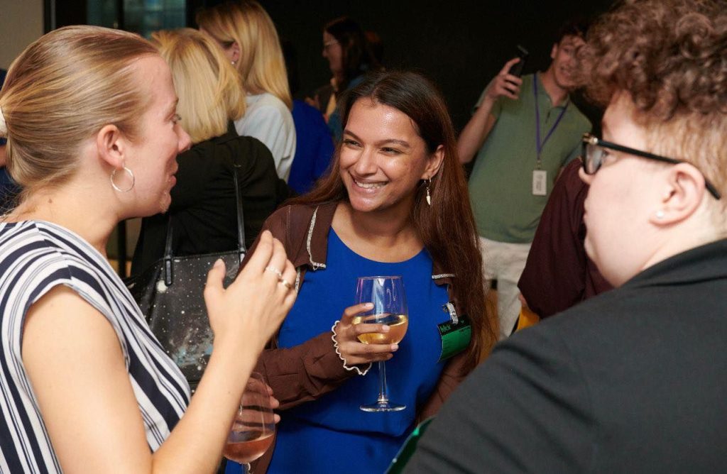 Women smiling in conversations with drinks in their hands